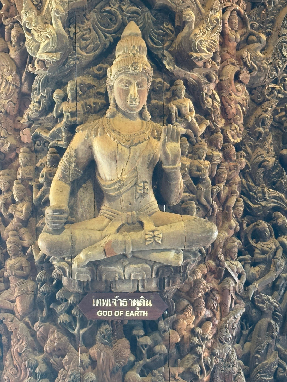 A detailed wooden carving inside the Sanctuary of Truth in Pattaya, featuring the “God of Earth” figure surrounded by intricate hand-carved deities and mythical designs.